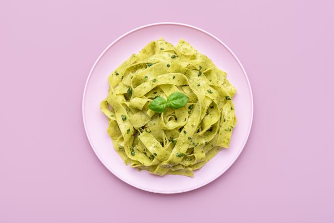 Pasta with pesto sauce minimalist on a pink background