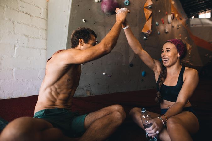 Man and woman rock climbers giving high five after successfully completing wall climbing