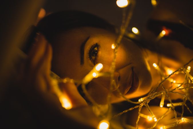 Woman lying surrounded by light garland