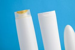 Variety of blank cosmetic bottles in blue room