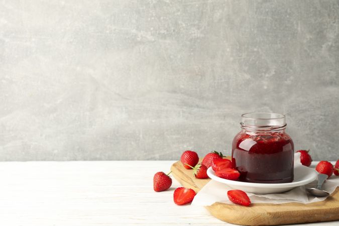 Composition with strawberry jam on wooden table against gray background