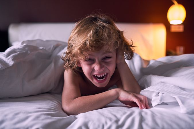 Excited child laughing on bed