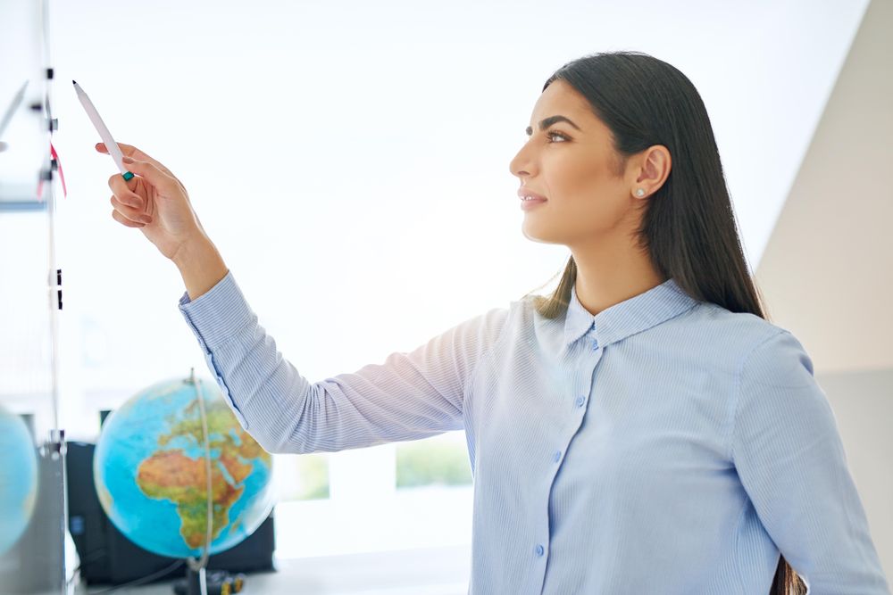 Serious female entrepreneur working off a dry erase board in bright office