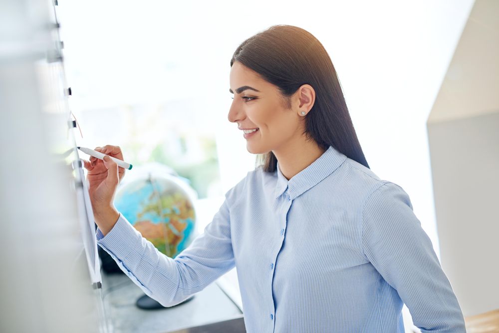 Smiling brunette woman writing on board for work
