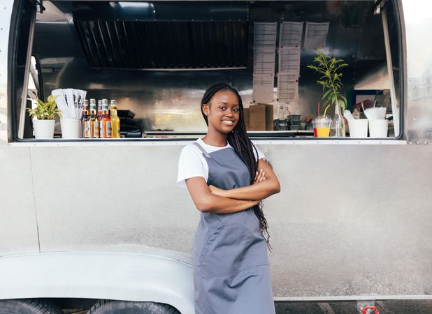 Proud young business owner outside her food truck in apron