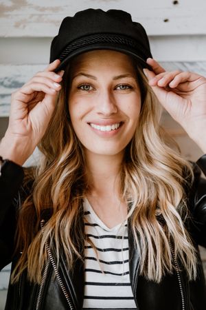 Woman thoughtfully looking at camera touching cap