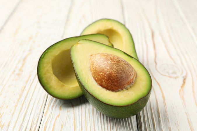 Ripe fresh avocado on plain wooden background, close up