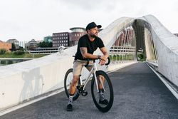 Cheerful man with bicycle standing on footbridge