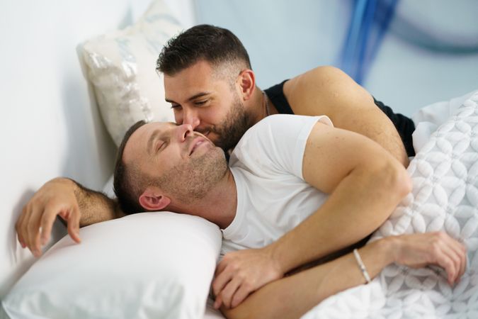 Two men kissing each other in bed