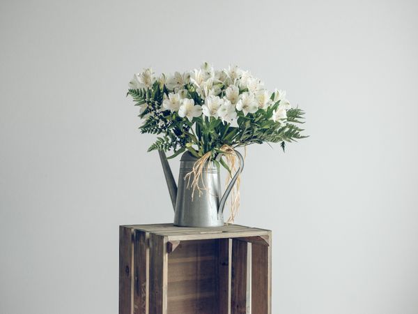 flowers in watering can on crate