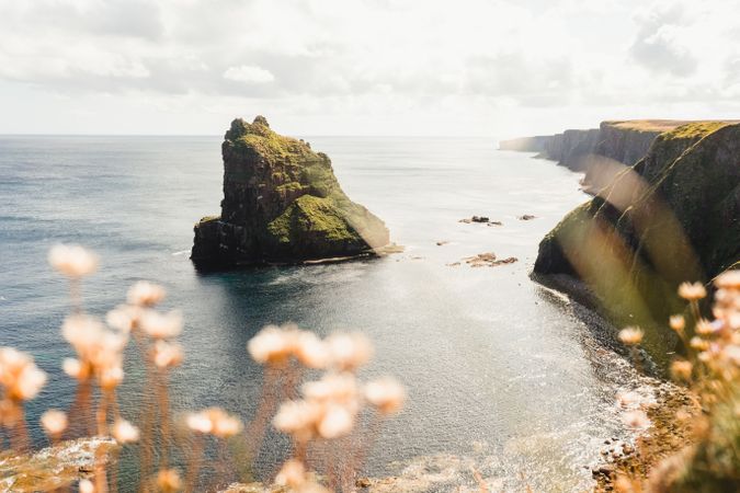 Rocky coast among tranquil ocean water in sunny day