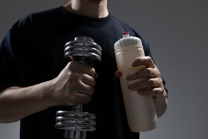 Man holding dumbbell and bottle