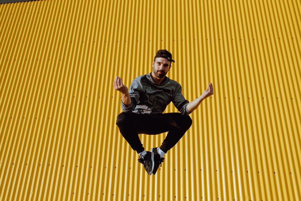 Man jumping near yellow wall