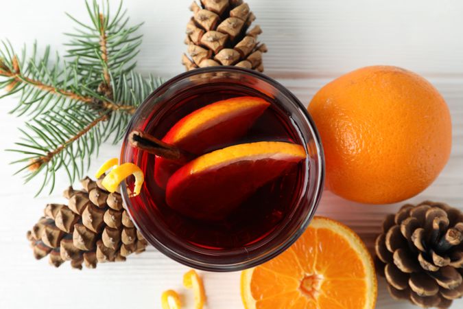 Glass of tasty mulled wine with orange on plain wooden background, top view
