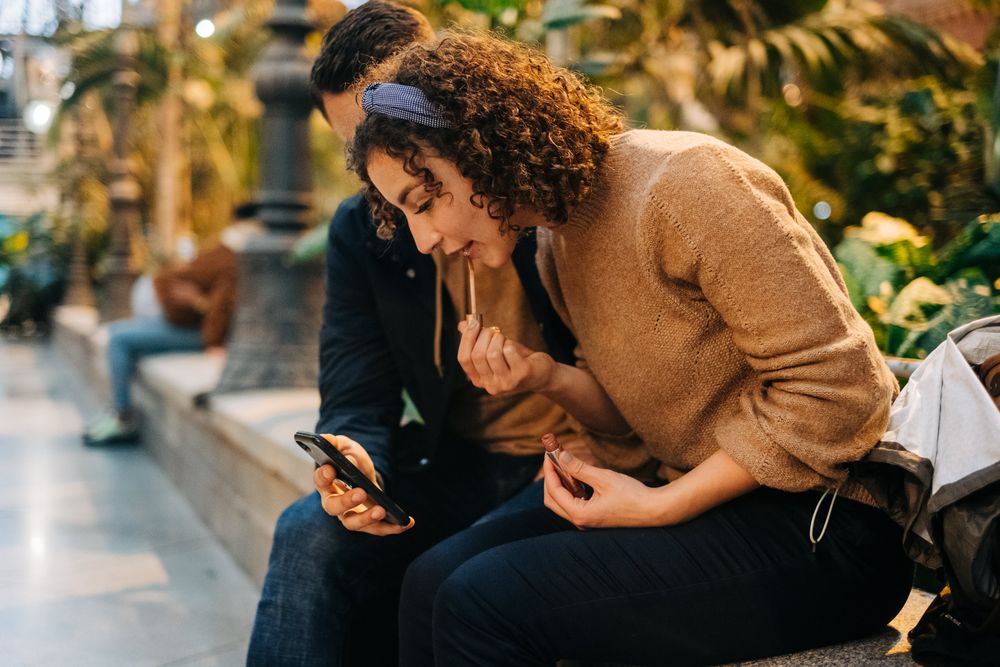 Couple using smartphone together on bench