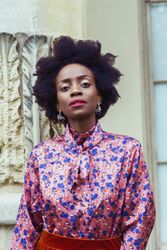 Portrait of Black woman with afro hair wearing pink floral shirt 47qQz0