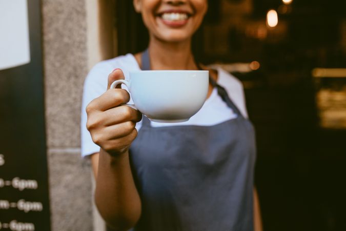 Focus on cup of coffee in hand of female cafe owner