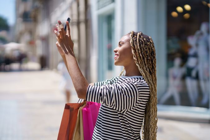 Female holding up smartphone taking a picture on street