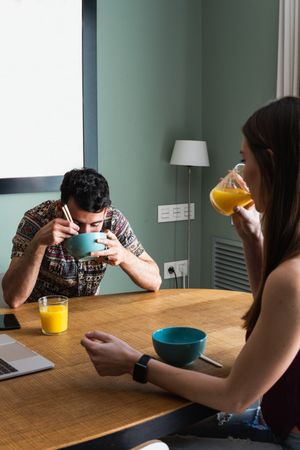 Happy friend having lunch and using laptop on dining table