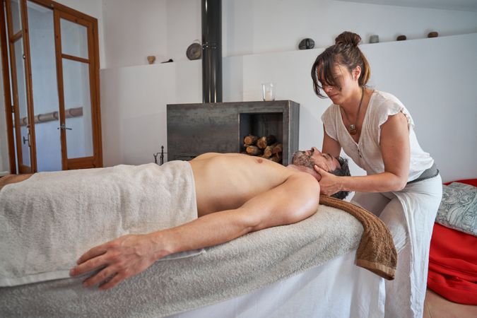 Masseuse kneading neck of male client at home
