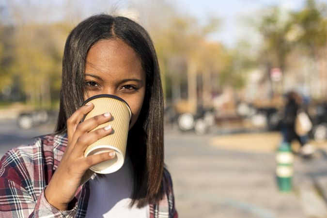 Female in plaid shirt drinking to go coffee