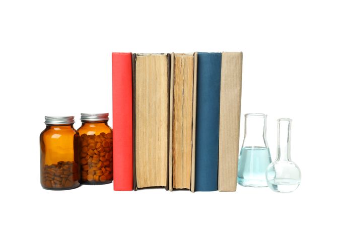Books, flasks and jars of pills, isolated on light background