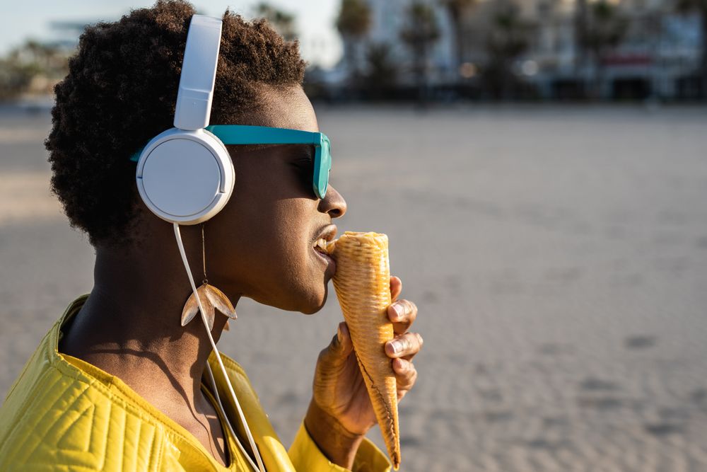 Cool female eating ice cream on beach