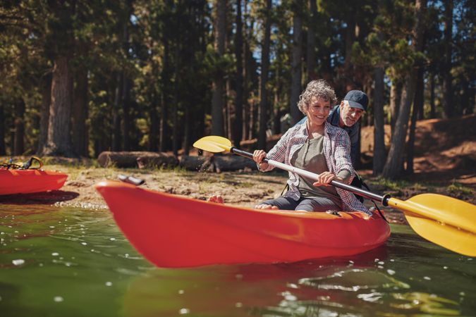 Portrait of mature woman learning to row in kayak with help from a man