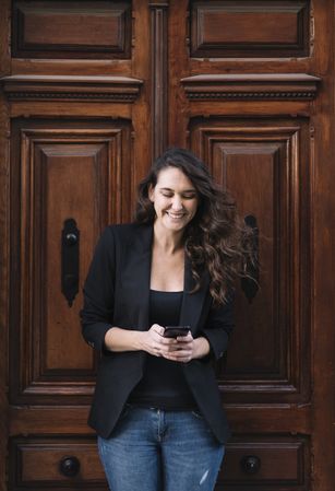 Young female using mobile phone on wooden door
