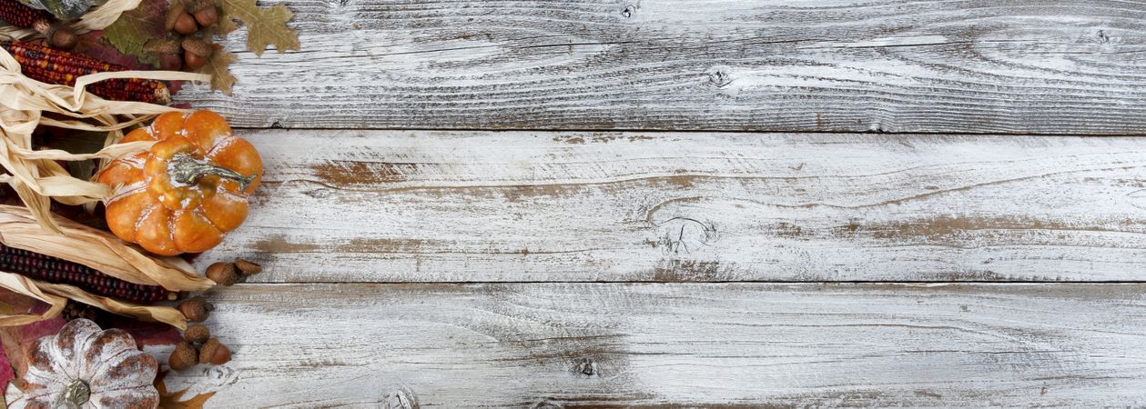 Autumn colorful leaves along other holiday decorations on rustic wooden background for the Thanksgiving holiday season