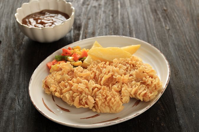 Crispy Chicken Steak with Potato Wedges, Sauted Vegetables, and Mushroom Sauce.
