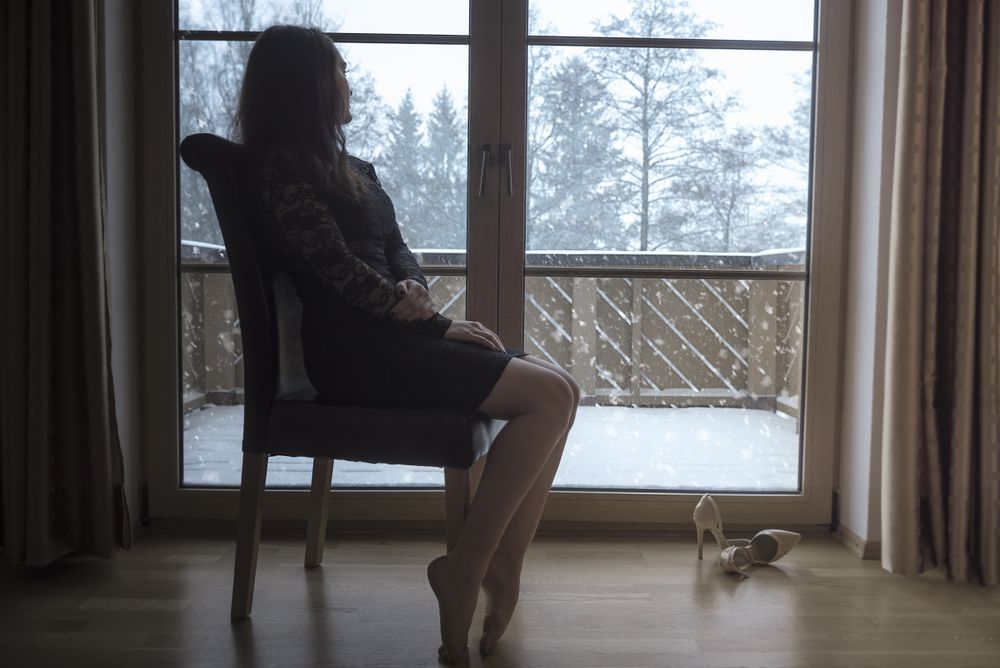Woman sits on a chair in front of glass doors