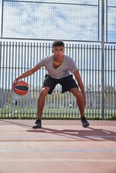 Latino man playing basketball on sports ground