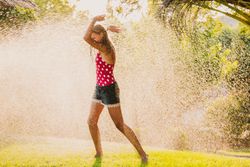 Cheerful teenager having fun with jet of water