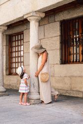 Mother and daughter walking in street along ancient building