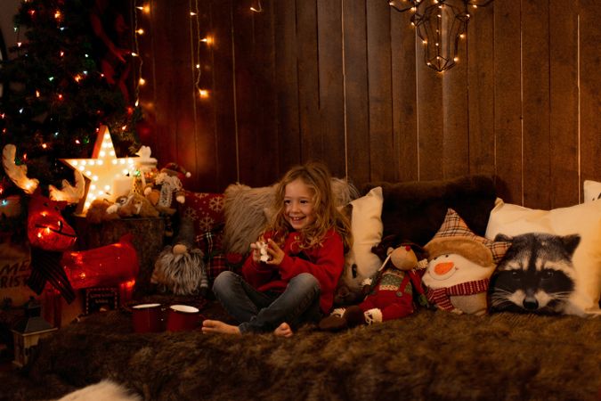 Little girl with teddy surrounded by christmas decoration