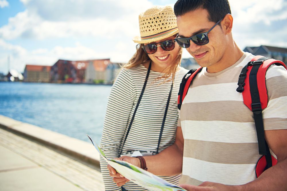 Smiling couple looking at guide or map along the riverfront