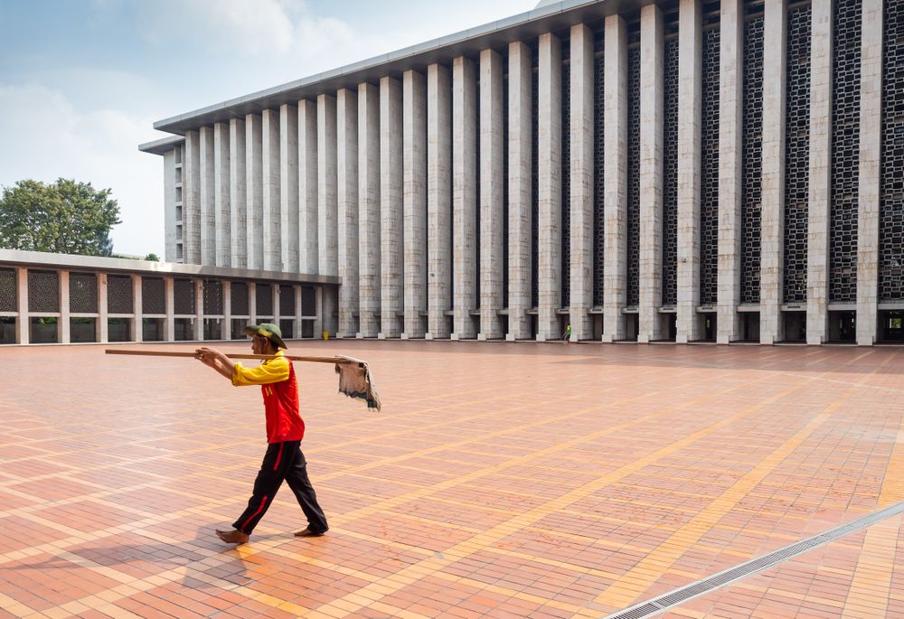Java Island, Indonesia - August, 14 2015: Barefoot janitor with mop in palace yard