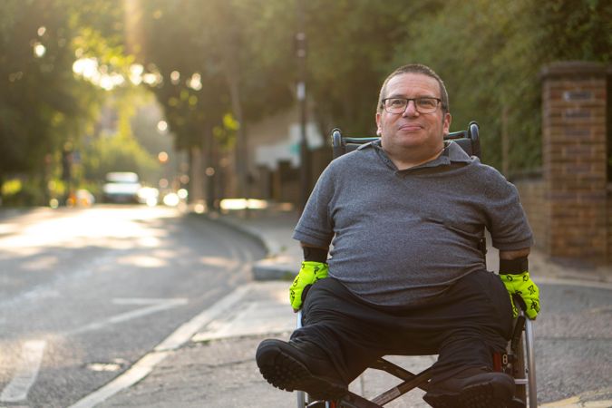 Man in wheelchair on sidewalk in quiet street