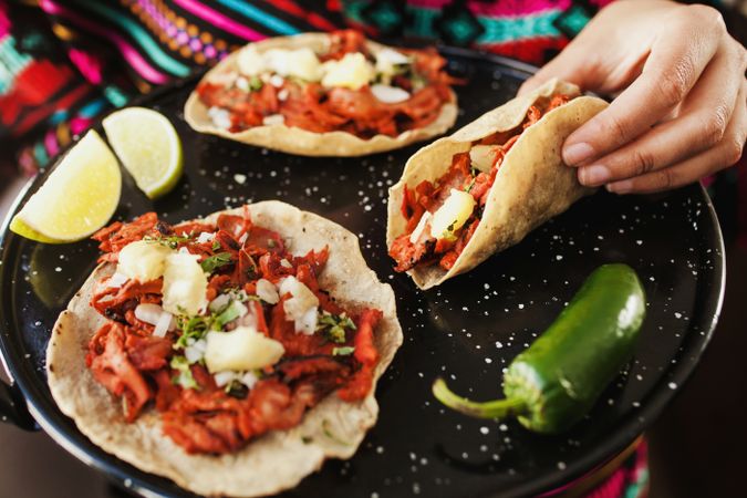 Crop hand holding taco al pastor