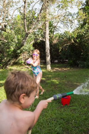 Little kids in swimwear having fun with splashing water