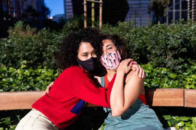 Two female friends in park together with protective medical masks