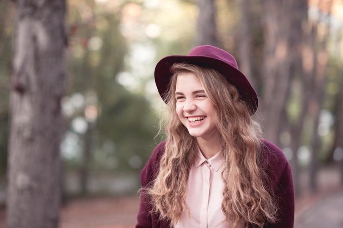 Portrait of cheerful teenage girl with purple hat standing outdoor