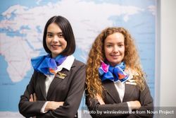 Two female flight attendants standing in front of map and smiling 5lzE7b