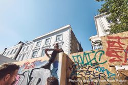 London, England, United Kingdom - August 25th, 2019: Man sitting atop barrier wall with graffiti 4NElD5
