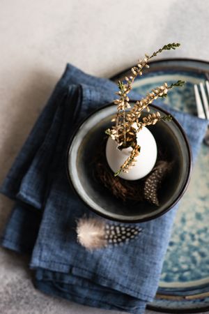 Top view of decorative egg with plant and feather on Easter table setting