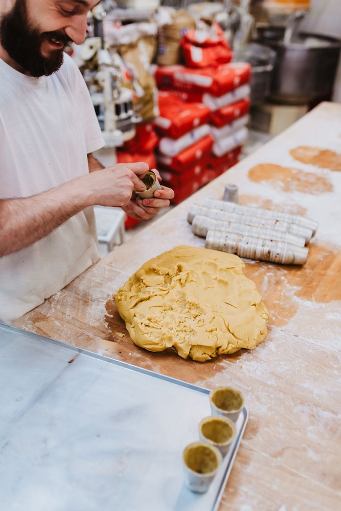 Bearded confectioner putting dough into cup