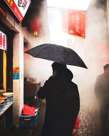 Back view of man holding an umbrella standing at the street market in Shanghai Shi, China