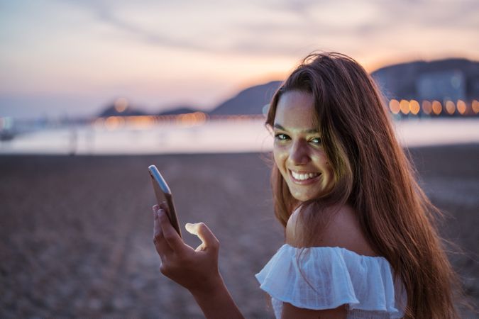 Cheerful young woman using smartphone on resort