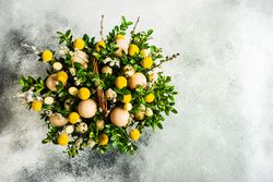 Top view of Easter card concept with fresh basket of greenery with decorative eggs